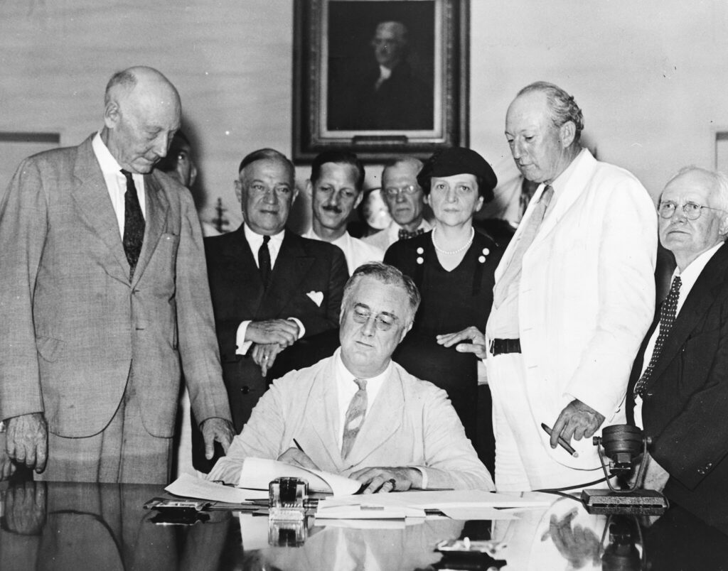 President Roosevelt signs the Social Security Act on August 14, 1935. It was designed to pay retired workers age 65 or older a continuing income after retirement.