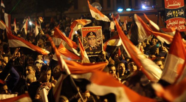 Egyptians wave the national flag and hold up pictures of Defense Minister army chief Abdel Fattah al-Sisi during a gathering in General Abdel Monim Riyad square at the edges of Cairo's Tahrir square on January 25, 2014. A spate of deadly bombings put Egyptian police on edge as supporters and opponents of the military-installed government take part in rival rallies for the anniversary of the 2011 Arab Spring uprising. 
