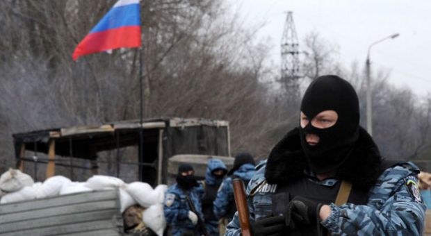 Armed masked men who call themselves members of Ukraine's disbanded elite Berkut riot police force stand at their checkpoint under a Russian flag on a highway that connect Black Sea Crimea peninsula to mainland Ukraine near the city of Armyansk, on February 28, 2014. The spiralling tensions in a nation torn between the West and Russia today took a severe new turn when Ukraine's interim president Oleksandr Turchynov accused Russian soldiers and local pro-Kremlin militia of staging raids on Crimea's main airport and another base on the southwest of the peninsula where pro-Moscow sentiments run high. 