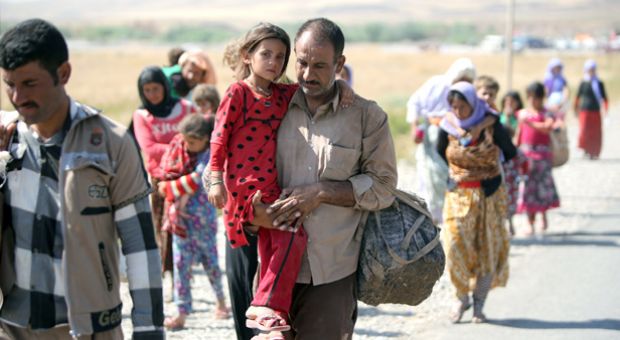 A displaced Iraqi man from the Yazidi community carries his daughter as they cross the Iraqi-Syrian border at the Fishkhabur crossing in northern Iraq, on August 11, 2014. At least 20,000 civilians, most of whom are from the Yazidi community, who had been besieged by jihadists on a mountain in northern Iraq have safely escaped to Syria and been escorted by Kurdish forces back into Iraq, officials said. 