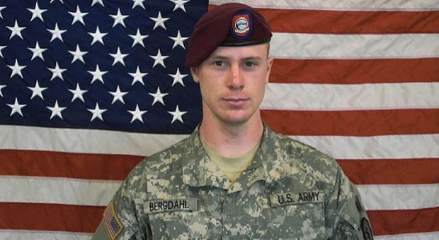 In this undated image provided by the U.S. Army, Sgt. Bowe Bergdahl poses in front of an American flag. 