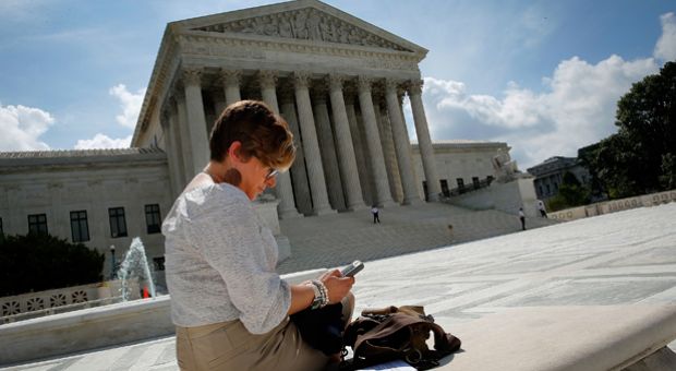Kirsten Luna from Holland, Michigan, uses her smartphone outside the U.S. Supreme Court after a major ruling on cell phone privacy by the court June 25, 2014 in Washington, D.C. The Supreme Court issued a ruling requiring law enforcement officials to have a search warrant to search the cellphones of suspects they arrest.  