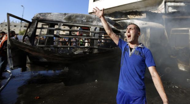 A Palestinian shouts slogans as firefighters try to extinguish the flames in a van, that was reportedly targeted by an Israeli military strike, in Gaza City on July 31, 2014.  

