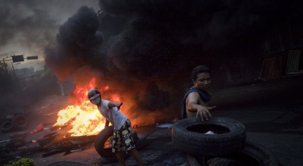 Anti-government "red shirt" supporters pile tires next to another barricade set ablaze between army soldiers and protesters near Bangkok's Victory Monument May 16, 2010
