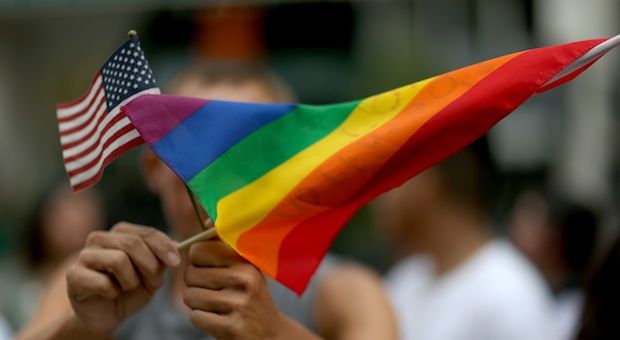 A protester holds an American flag and rainbow flag in front of the Miami-Dade Courthouse to show his support of the LGBTQ couples inside the courthouse were asking the state of Florida to recognize their marriage on July 2, 2014 in Miami, Florida. 